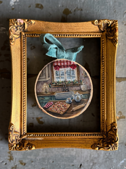 a hand-painted Christmas cookie scene on a wood slice with a blue velvet bow presented in an ornate gold frame